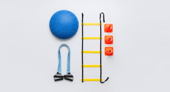A collection of neuromotor exercise equipment including a foam balance pad, an agility ladder, and resistance bands.